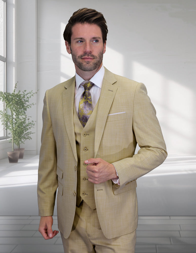 A man in the STATEMENT CLOTHING | LARZO-TAN modern fit sharkskin suit with matching vest by Statement Clothing stands indoors near a window and potted plant, wearing a patterned tie.