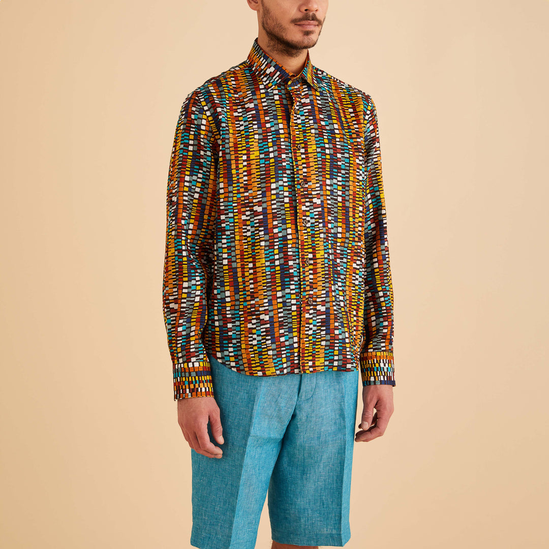 Person wearing an Inserch LS Geo Print Linen Shirt in cacao and blue shorts, standing against a plain beige background.