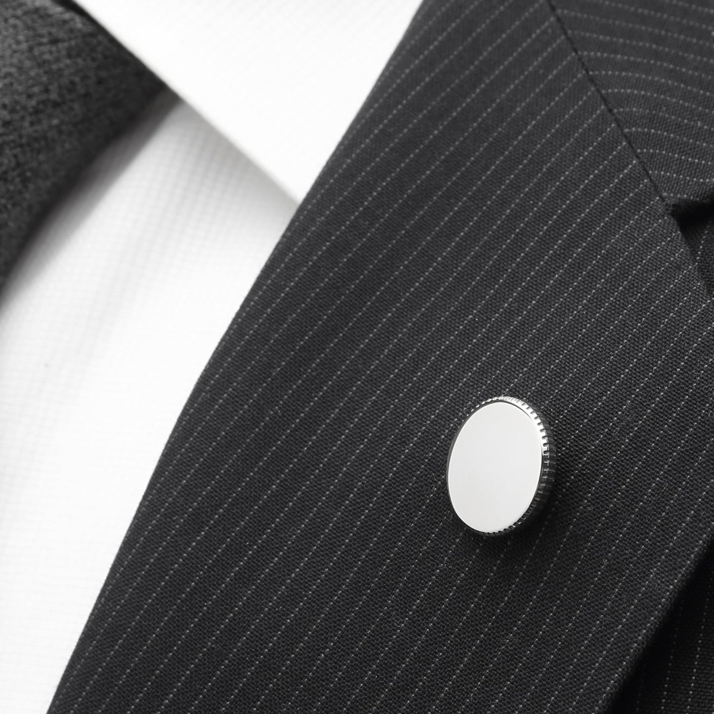 The Cufflinks.com Stainless Steel Coin Edge Engravable Lapel Pin features a round, silver-colored design with a textured coin edge and a smooth, flat front, perfect for engraving.