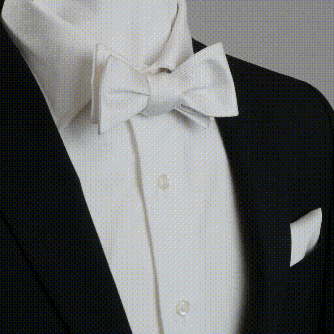 The White Silk Self Bow Tie by Cufflinks.com features ribbed silk fabric, an adjustable strap, and is shown tied and untied.