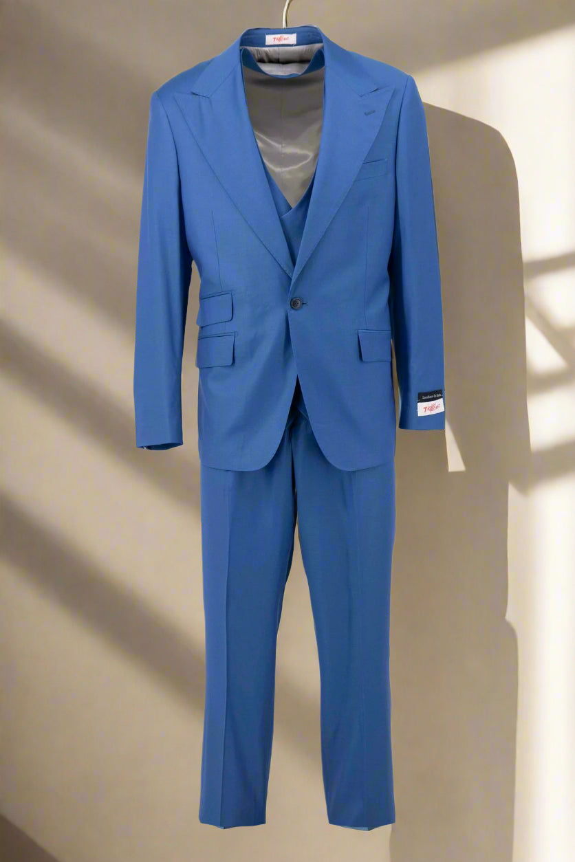 A man wearing the Tiglio Rosso Orvietto Azure Semi Wide Leg TL7118 three piece suit by Tiglio Rosso, paired with a white shirt and patterned tie, stands facing forward against a plain light background.