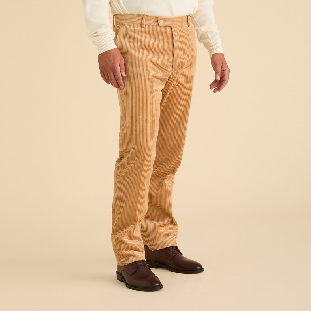 A person wearing Inserch Cotton Corduroy Pants P267-09 Khaki, a cream sweater, and brown dress shoes stands against a beige background.
