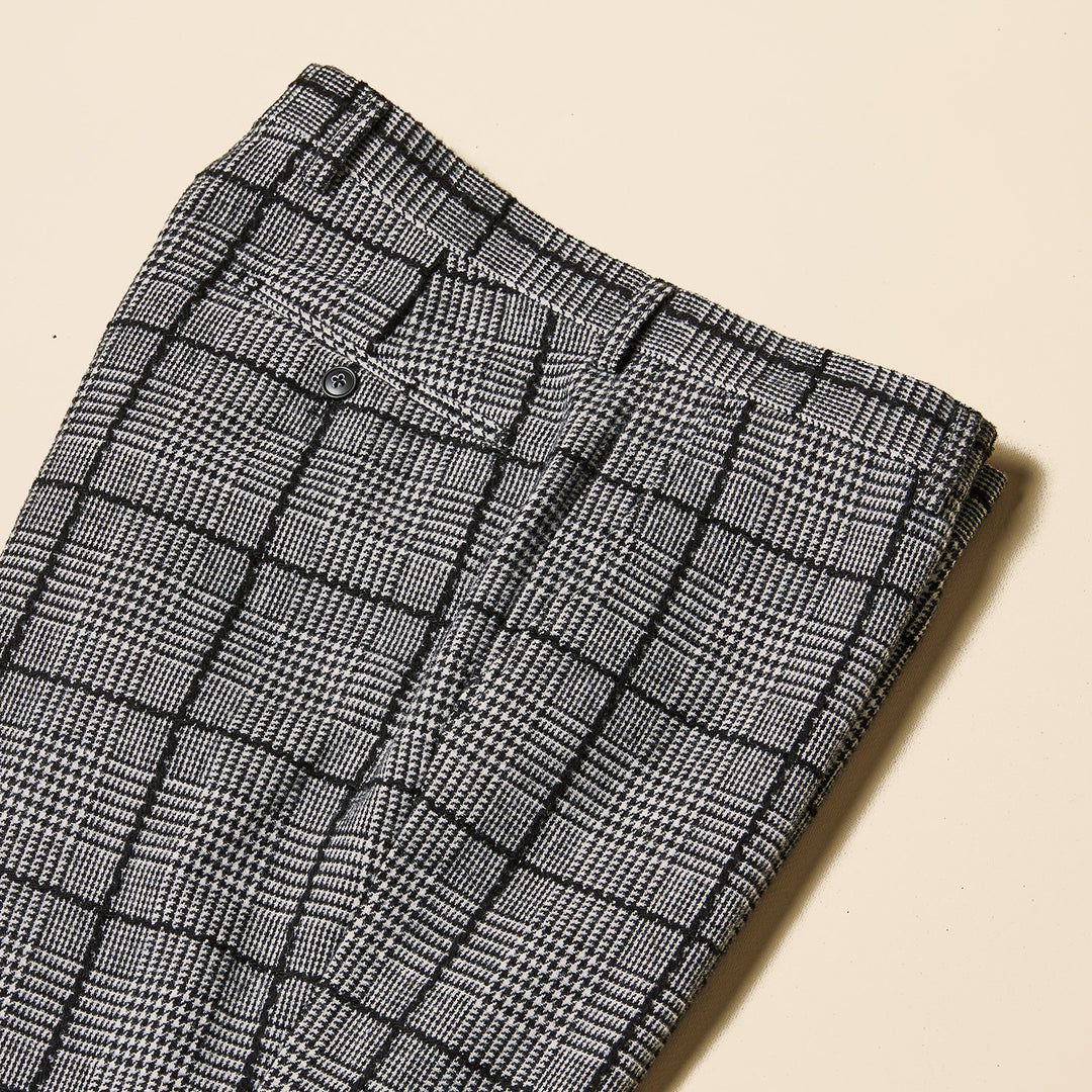 A man poses facing forward in the Inserch DB Glenn Check Suit BL504-41 Black/White, featuring a modern fit plaid blazer, black turtleneck, and black shoes by Inserch, set against a plain beige background.