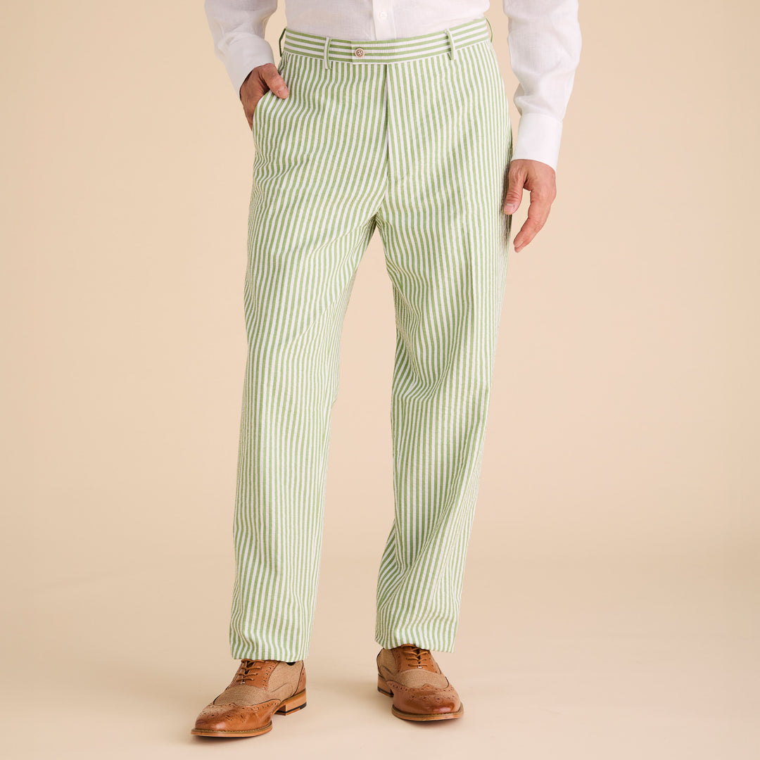 A person wearing a premium white cotton shirt, Inserch Seersucker Stripe Pants P660155-00018 Kiwi, and brown brogue shoes stands against a beige background.