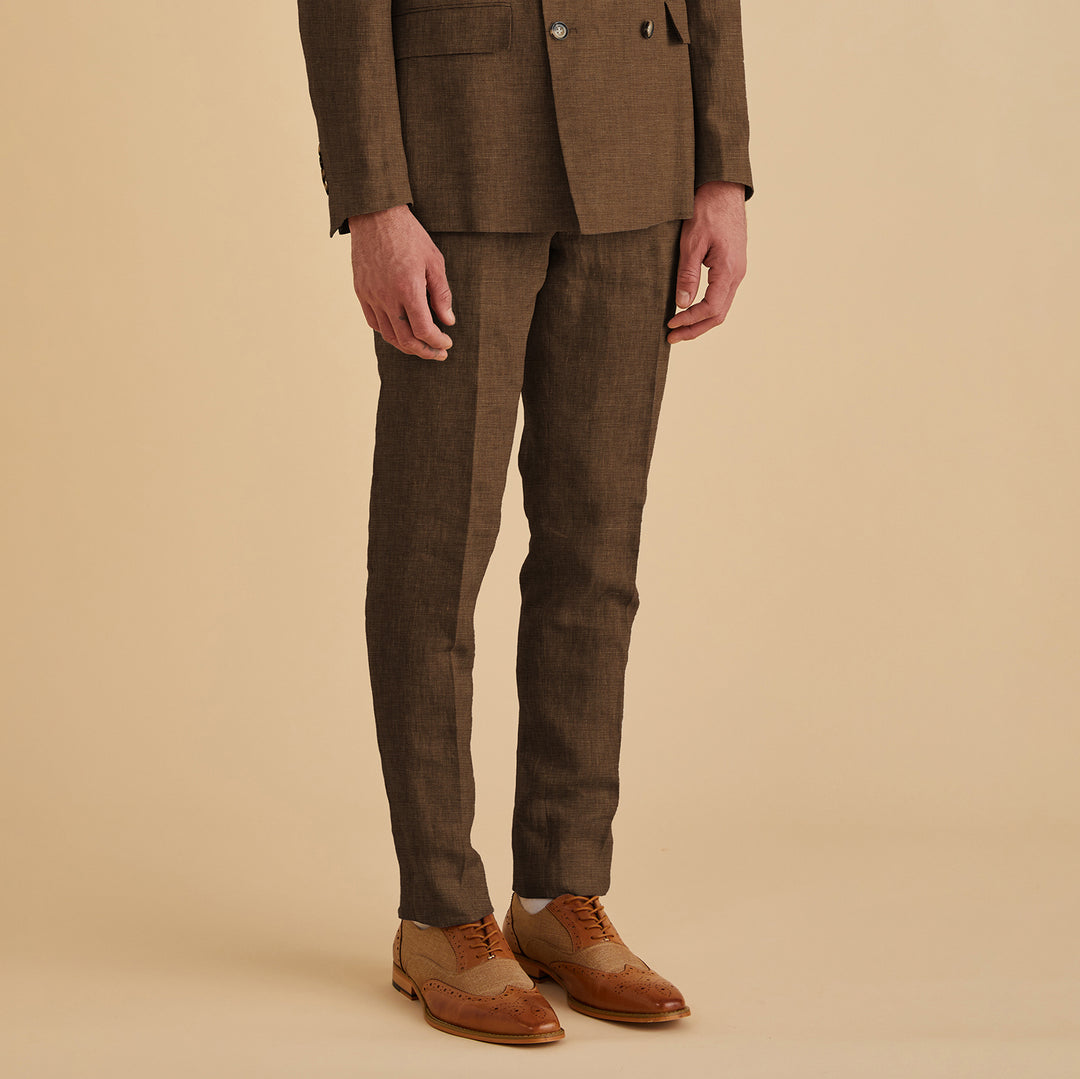 A person stands confidently against a beige background in Inserch's Slim Linen Pants P880-00064 Mocha, part of a matching brown slim-fit suit, paired with tan dress shoes.