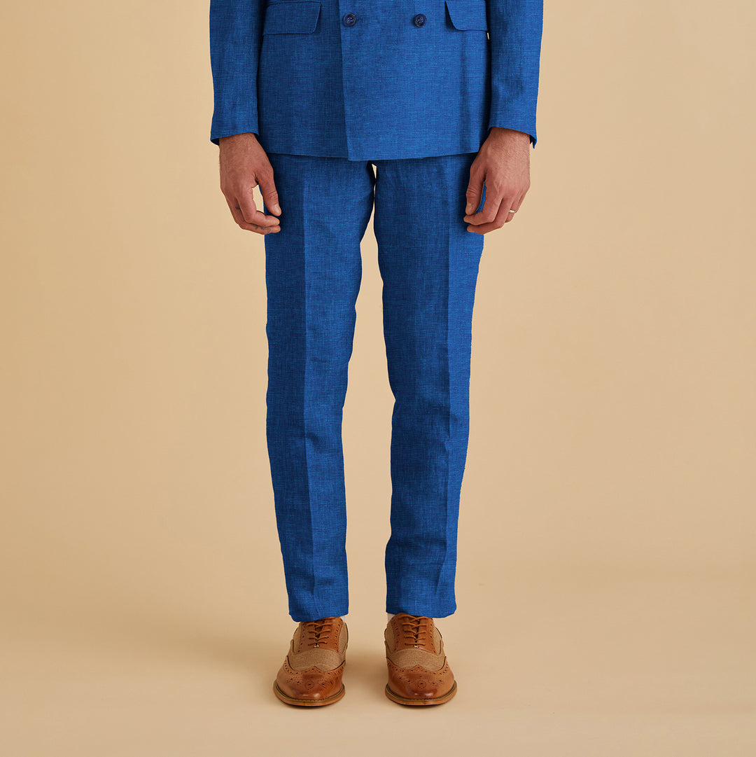 A person wearing Inserch Slim Linen Pants P880-00181 River Blue and brown dress shoes stands against a beige background.