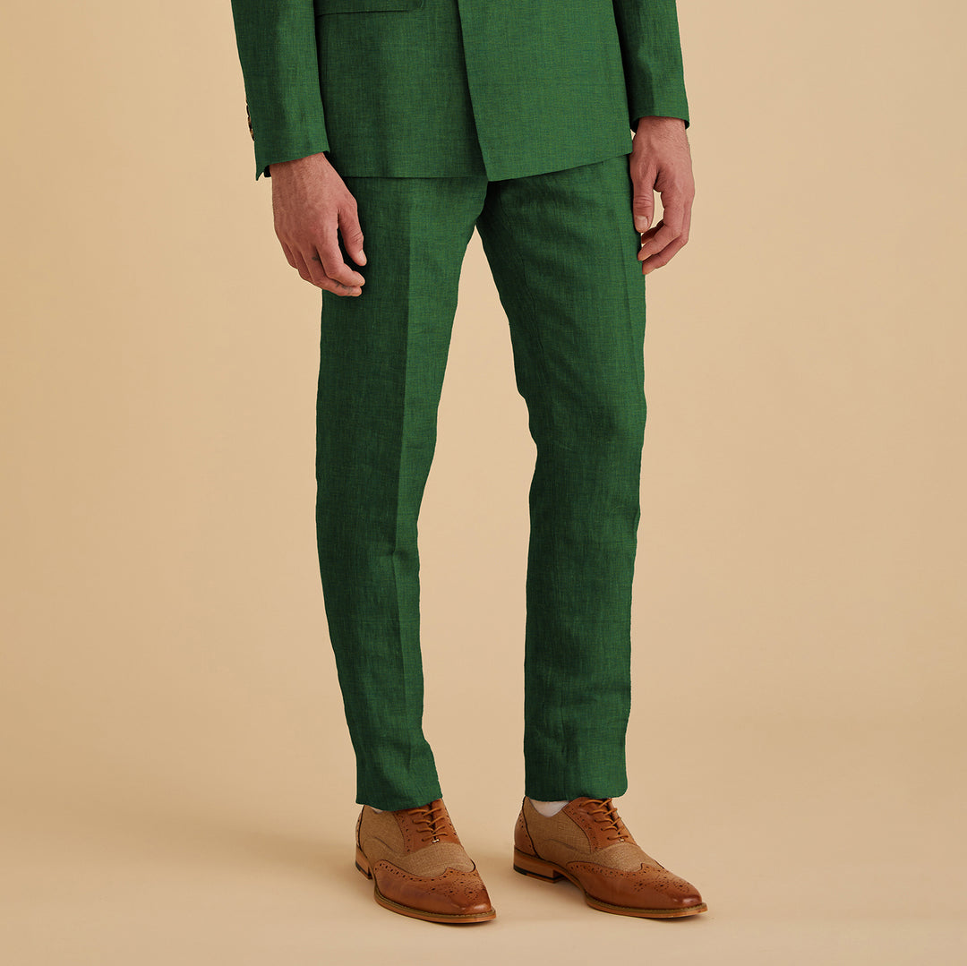 A person wearing Inserch Slim Linen Pants P880-00200 in emerald stands against a beige background, paired with brown brogue shoes.