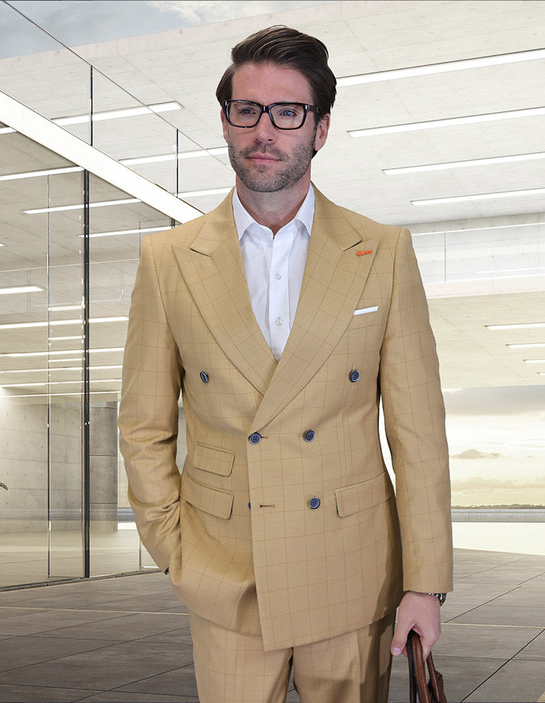 A man in the STATEMENT CLOTHING | SD-104-CAMEL modern fit, light tan double-breasted suit from Statement Clothing, paired with a white shirt and glasses, stands in a glass-walled building with his hand in his pocket.