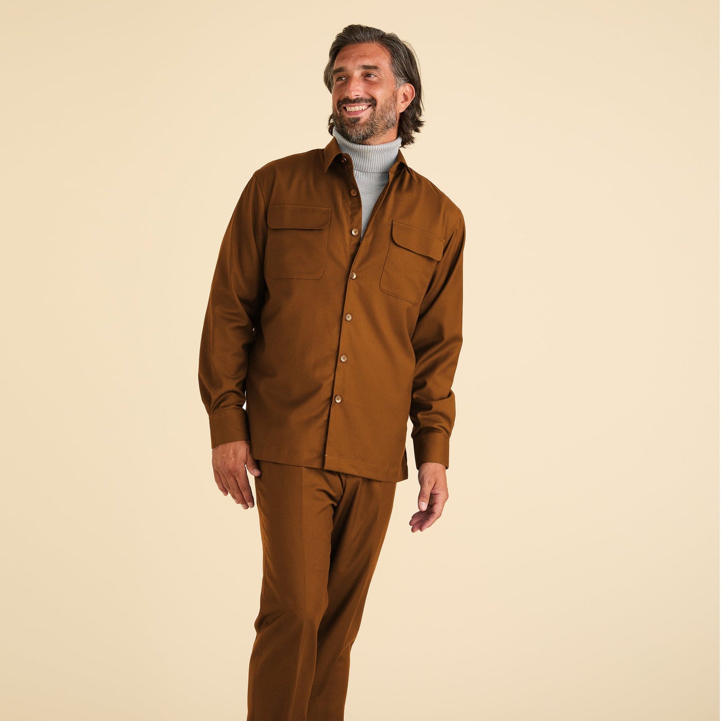 A man stands against a beige background wearing Inserch Modern Fit Pants P3199S-27 Aztec and a brown shirt over a light gray turtleneck.