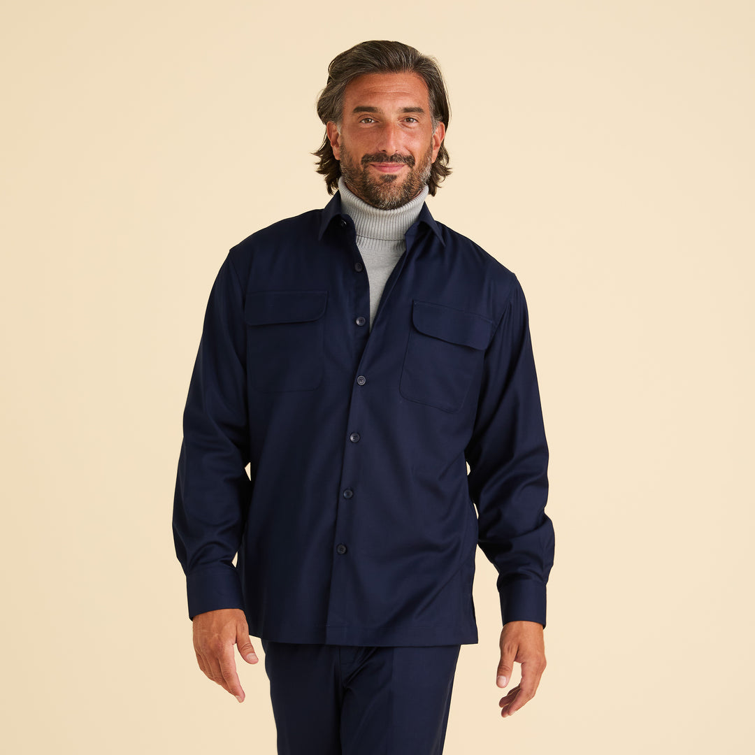 A man with medium-length brown hair and a beard models the Inserch Two-Pocket 2pc Set SE004-36 Ink by Inserch, featuring a navy shirt over a light gray turtleneck, paired with modern fit trousers, against a plain beige background.