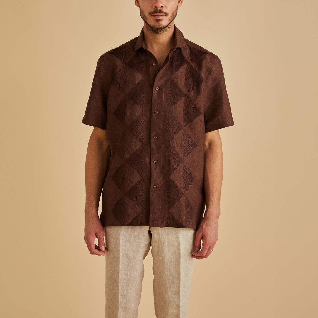 A man wearing the Inserch SS Linen Embroidered Shirt SS126-00024 in chocolate and beige pants stands against a plain beige background.