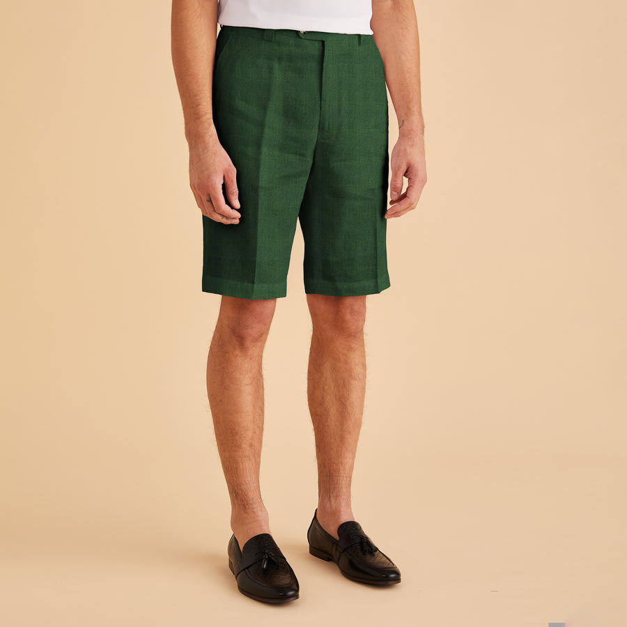 An individual wearing a modern-fit white shirt, Inserch Modern Linen Shorts ST31-00200 Emerald, and black shoes stands against a beige background.