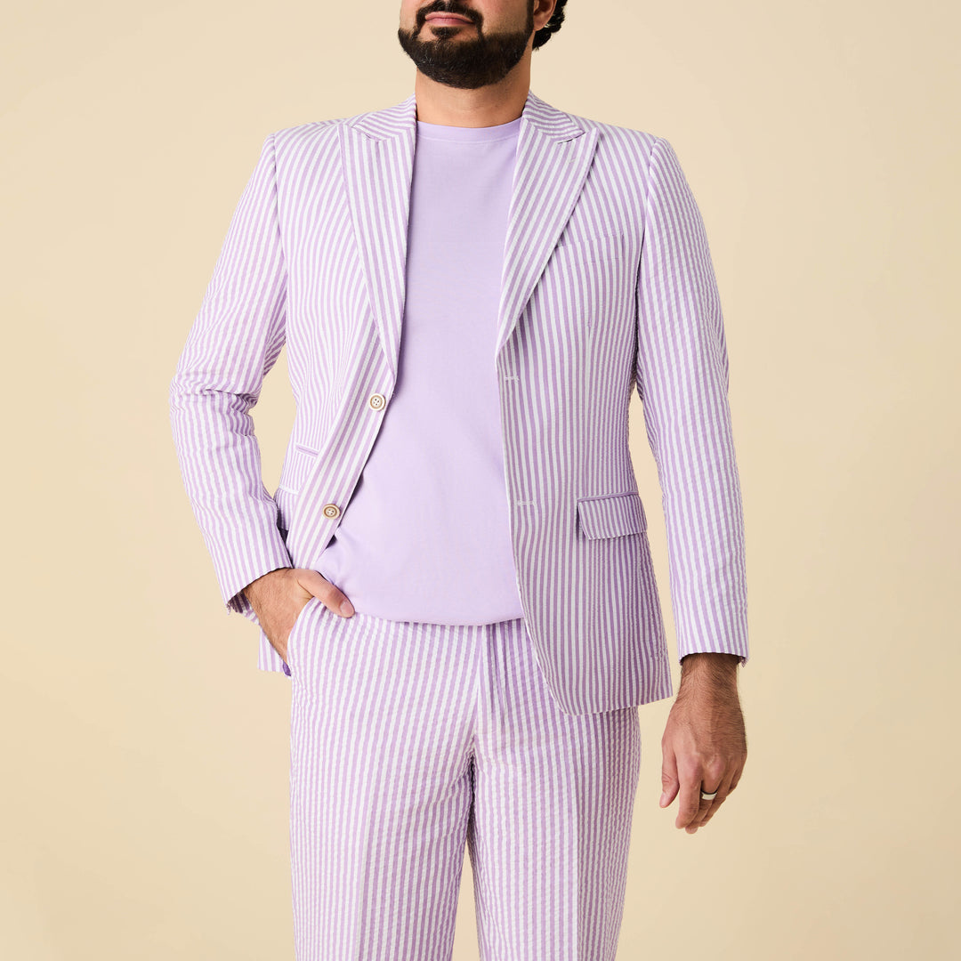 A person wearing the Inserch Seersucker Stripe Blazer SU660155-00119 Lavender by Inserch stands against a beige background, paired with matching seersucker pants and a lavender t-shirt.