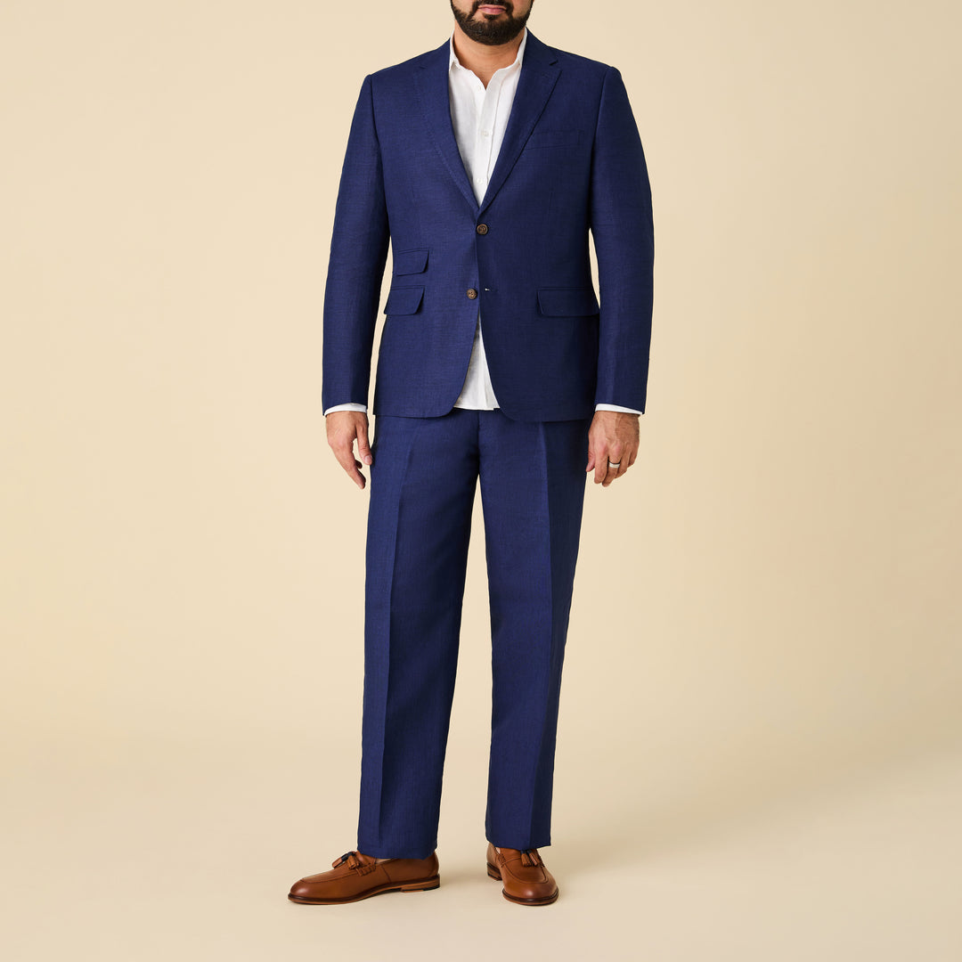 A man stands against a beige background wearing an Inserch Slim Linen Blazer SU880-00150 Summer Navy over a white dress shirt and brown dress shoes.