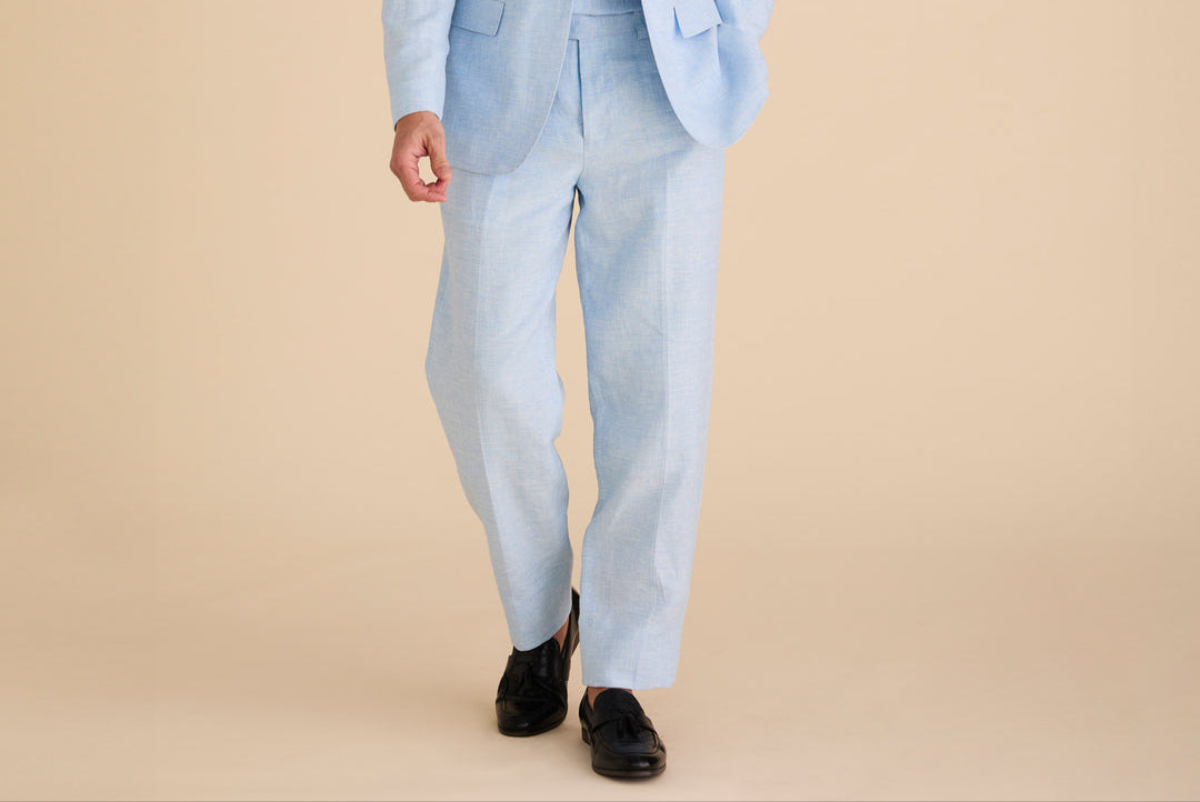 A person elegantly wears an Inserch Slim Linen Blazer SU880-00183 in Blue Mist paired with black shoes, set against a plain background.