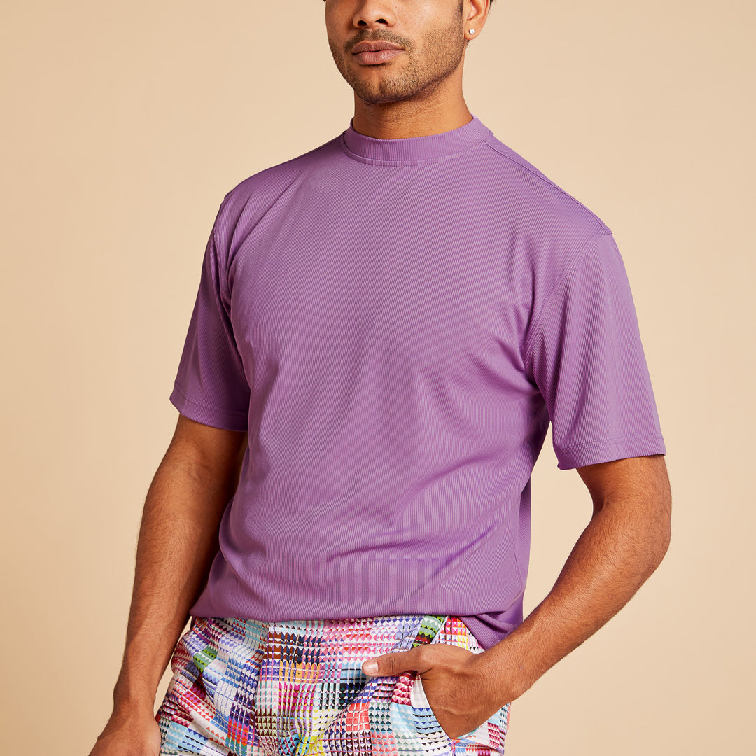 A person wearing the Inserch Rib Crew Neck T-Shirt T299-00119 Lavender and colorful checkered pants stands against a beige background.