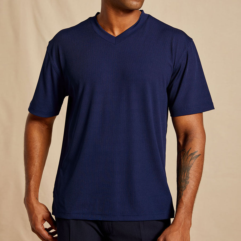 A person wears the Inserch Rib V Neck T-Shirt T300-00011 in navy blue by Inserch, featuring short sleeves and a soft polyester/spandex blend, while standing against a beige background.