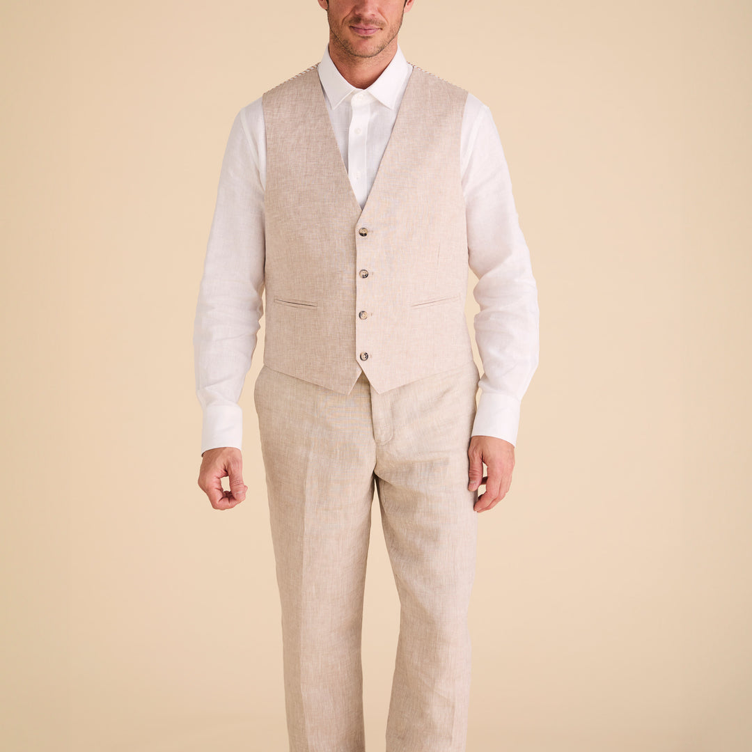A person stands wearing the Inserch Classic Linen Vest V660-00006 Oatmeal with matching pants, paired with a white long-sleeve shirt, set against a plain beige background.