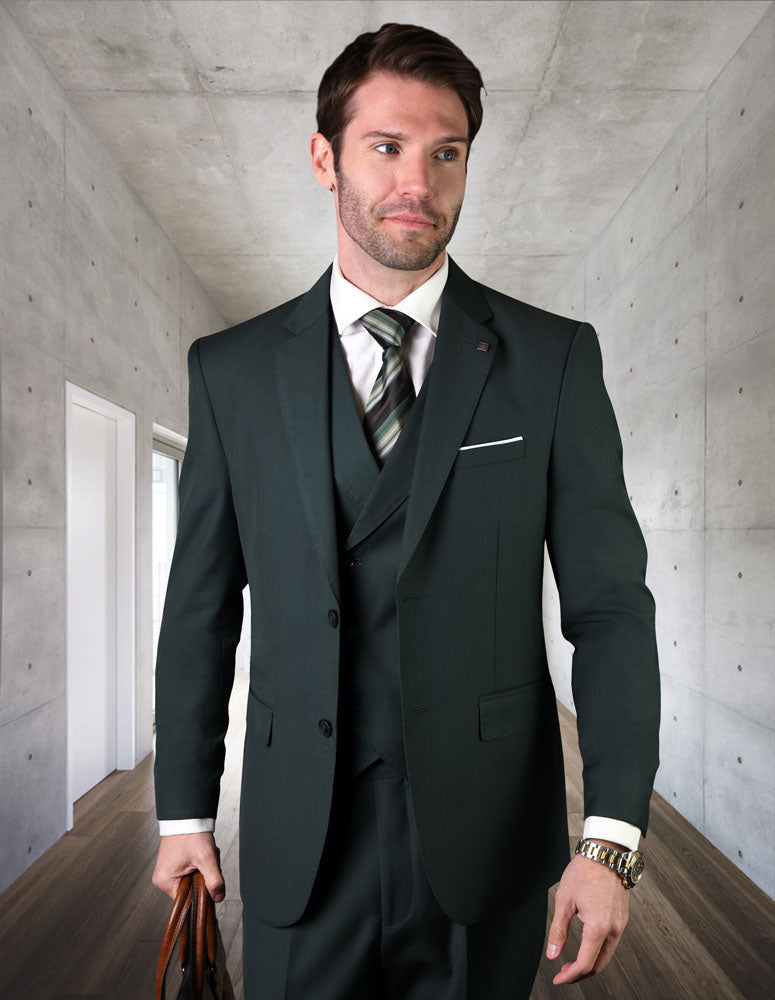A man wearing the STATEMENT CLOTHING | ZARGALA-HUNTER by Statement Clothing—a modern dark suit with a striped tie and double-breasted vest—stands in a sleek concrete-walled hallway, holding a brown briefcase.