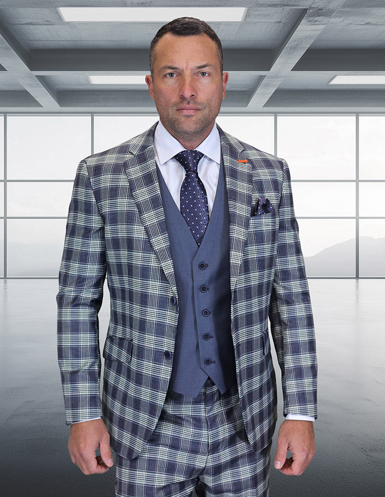 A man in the STATEMENT CLOTHING | ZILONI-2-GRAY modern fit Italian wool suit by Statement Clothing stands in a sleek, empty room with large windows and gray flooring.