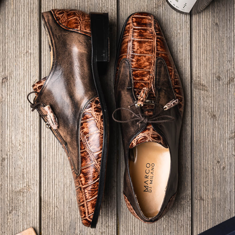 A pair of Anzio Rustic Orix brown leather dress shoes by Marco Di Milano, featuring a textured crocodile pattern—one upright, the other showing a smooth tan sole—represent true luxury men's footwear.
