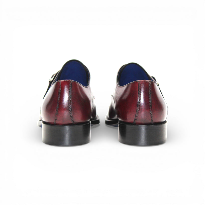 The Emilio Franco Bernardo Burgundy men's leather dress shoe features a silver buckle strap, black sole, and slight heel, stylishly displayed on a white background.