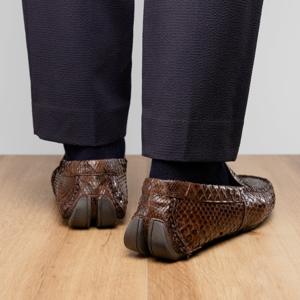 A pair of Capri Brown luxury exotic shoes by Marco Di Milano, crafted from genuine python leather, with one handcrafted men’s loafer standing upright and the other displayed on its side to highlight the intricately textured sole.