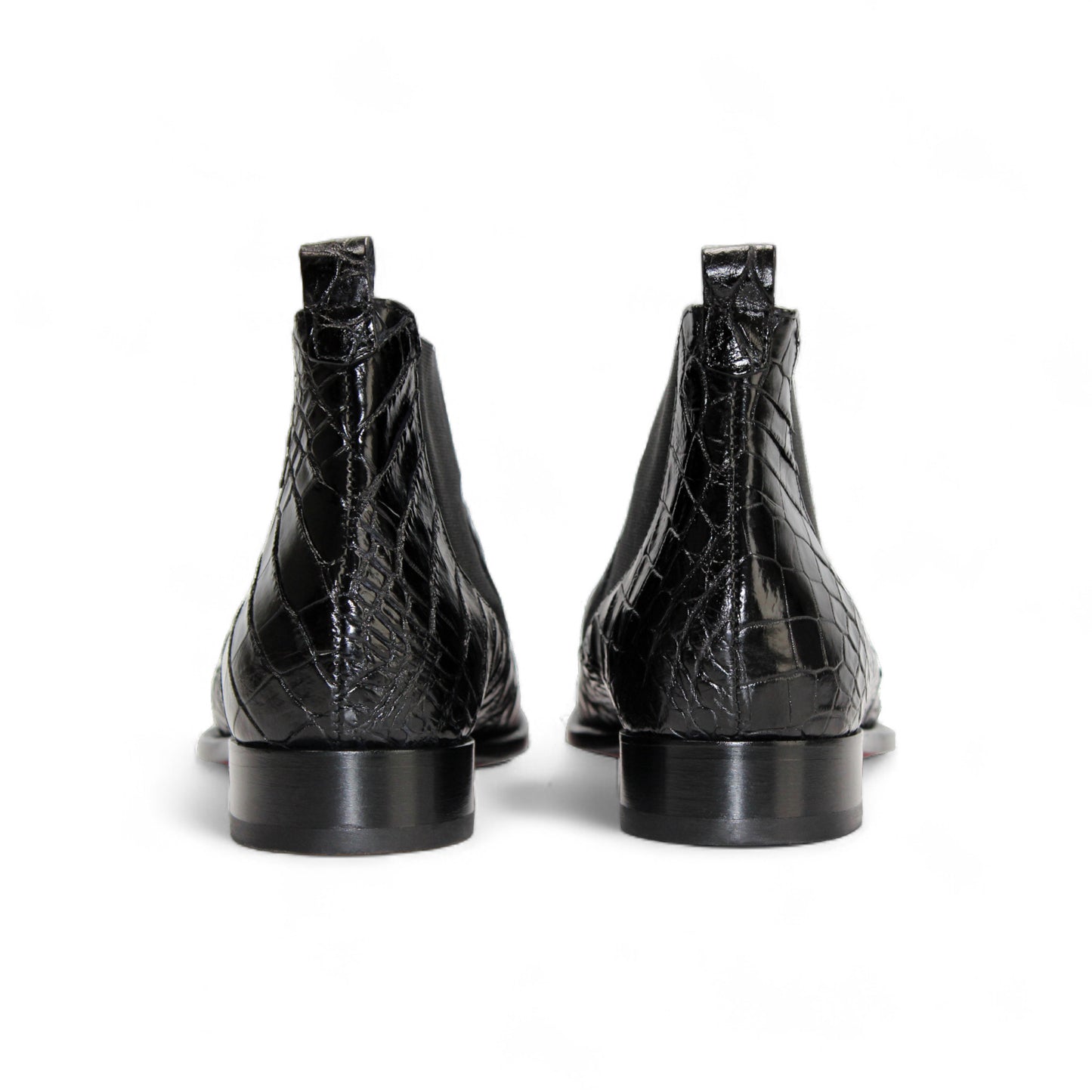 The Fennix Cole Black by Fennix of Italy is a luxury Chelsea boot in genuine alligator leather with a crocodile pattern, elastic side panel, low heel, and bold red sole accent—elegantly displayed in profile.