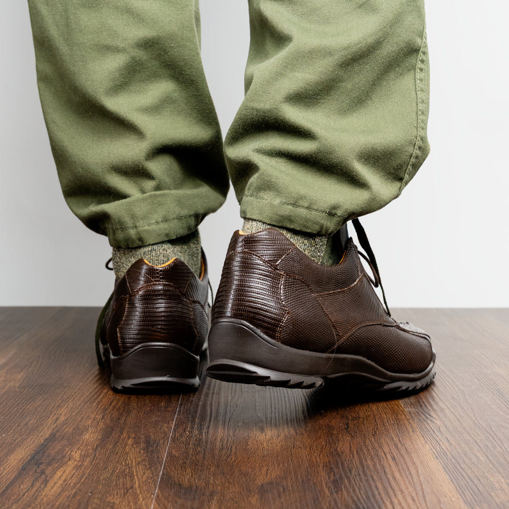 The Crater Brown by Marco Di Milano features brown textured leather with crocodile pattern accents, gold "MD" logos, and black rubber soles, blending dress shoe elegance with caiman hornback sneaker style.