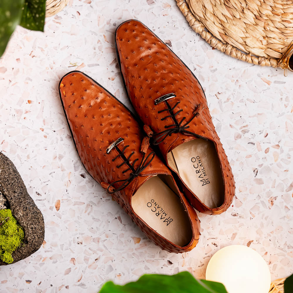 A pair of Criss Brandy genuine ostrich quill leather luxury dress oxfords by Marco Di Milano, with one shoe upright and the other sole up to display the brand name.