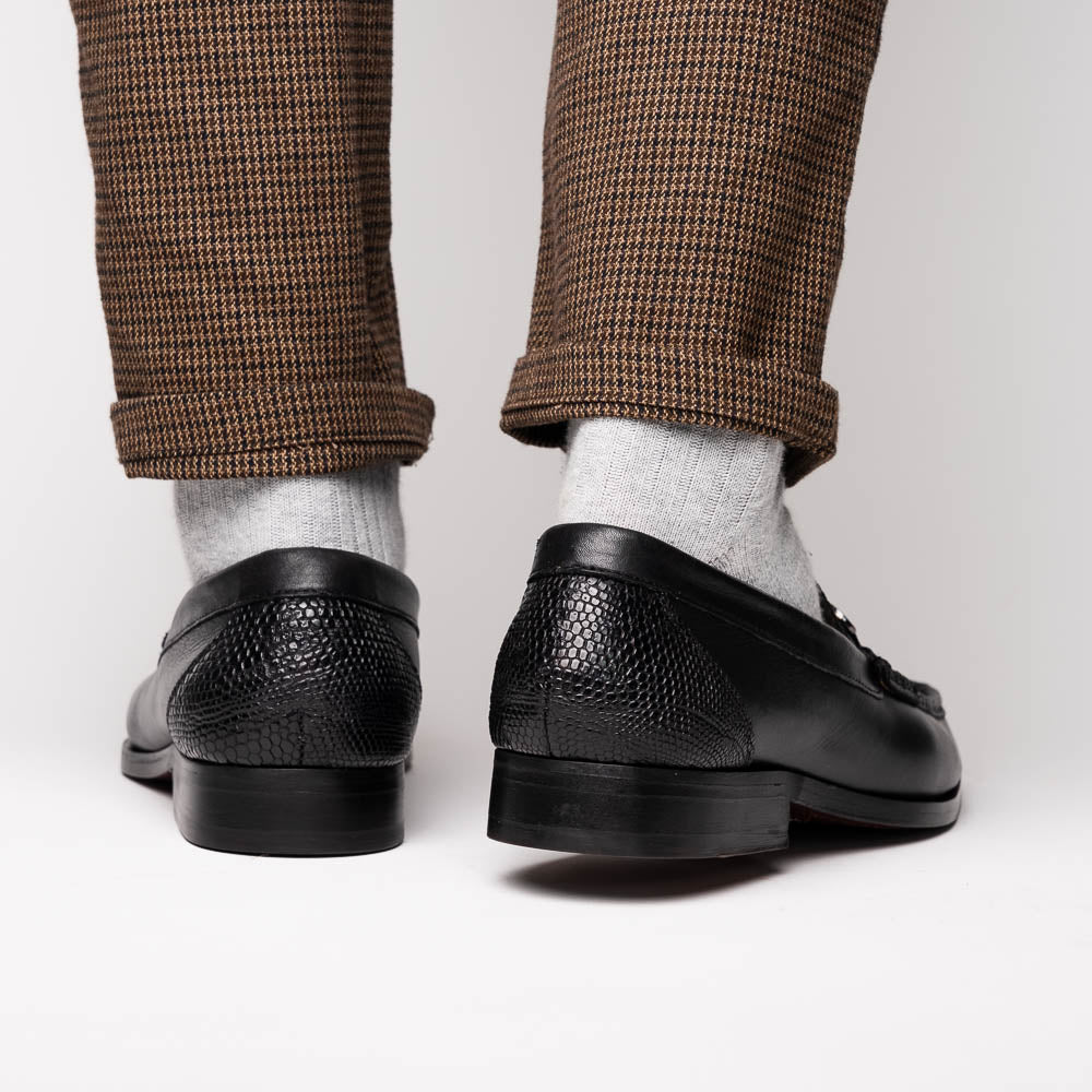 The Enzo Black by Marco Di Milano: black textured genuine lizard loafers with metal bit detail—one upright, one showing a brown sole stamped with "MARCO DI MILANO"—perfect for fans of luxury men's footwear.