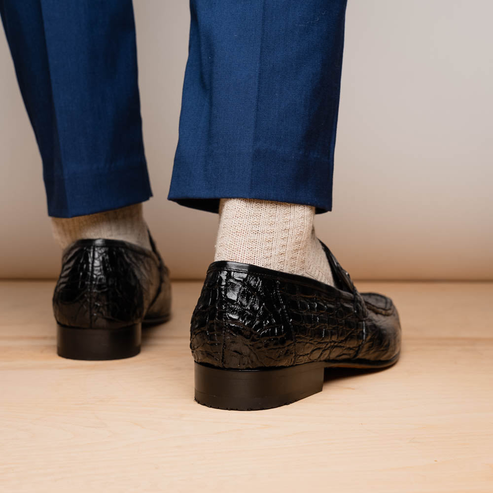 A pair of Fabro-Tin Black textured men's shoes by Marco Di Milano, featuring metal accents—one upright and one on its side showing the branded tan sole.