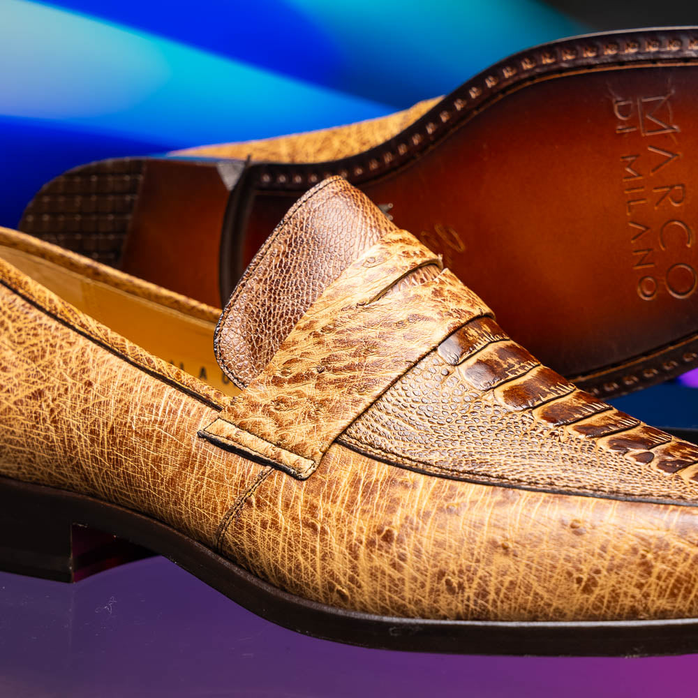 The Fangio Orix by Marco Di Milano: tan textured genuine ostrich loafers with dark brown soles, one upright and one on its side to display the sole—luxury men's shoes with hand-painted finishes.