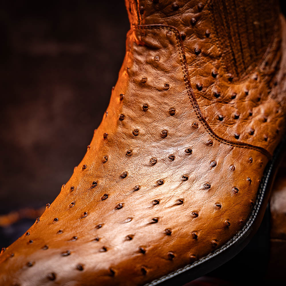 The Giorgio Brandy dress boots by Marco Di Milano feature genuine brown ostrich quill leather, hand-painted finishes, a side zipper, and a textured design—one upright and one lying down to showcase the sole's craftsmanship.