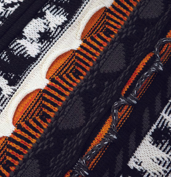 A man wears the Inserch 3D Intarsia Full Zip Sweater SW907-01 in black, featuring white, black, and orange vertical stripe jacquard panels.