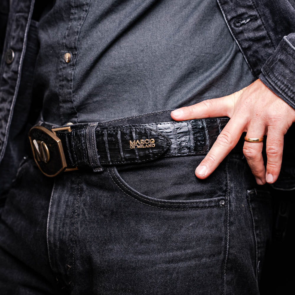 The Iowa Belt Black by Marco Di Milano is crafted from genuine black caiman skin with a crocodile texture, featuring a bold gold "MD" buckle and embossed branding—an eye-catching Western belt for any outfit.
