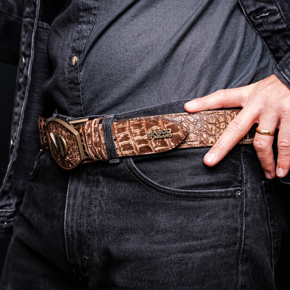 The Marco Di Milano Iowa Belt Stone Brown features genuine caiman crocodile leather, a gold "MD" buckle, and "Marco Milano" engraved on the side, evoking a classic western style against a white background.
