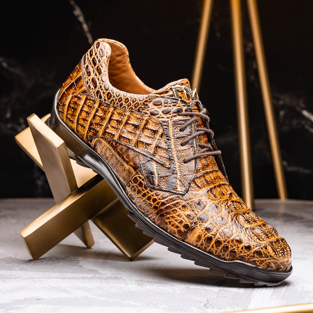 A pair of Kratos Rustic Orix brown crocodile-patterned leather dress shoes by Marco Di Milano, one upright and one tilted to display the textured sole, showcasing luxury footwear against a white background.