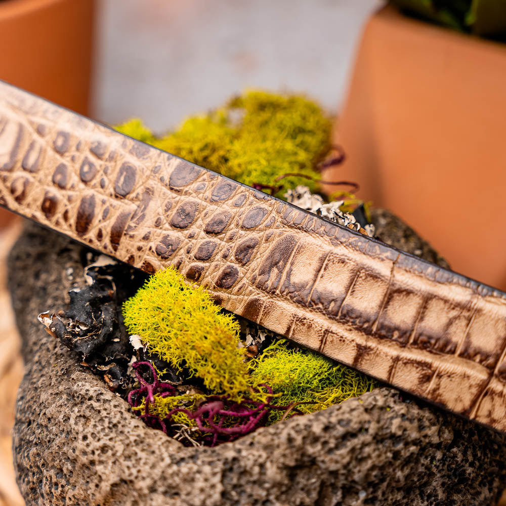 The Riccardo Belt Rustic Orix by Marco Di Milano features brown crocodile-patterned genuine caiman fuscus-belly leather and a metal buckle engraved with the brand's logo and "MD" initials.