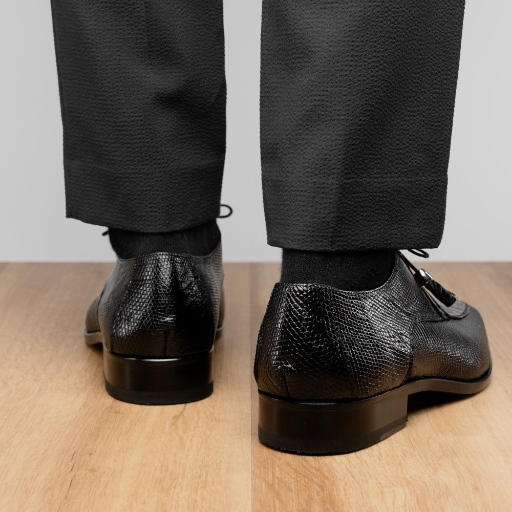A pair of Merida Black dress derby shoes by Marco Di Milano, crafted from textured black leather caiman—one upright and one on its side revealing the brown sole stamped with the brand’s logo—an unmistakable statement in luxury footwear.