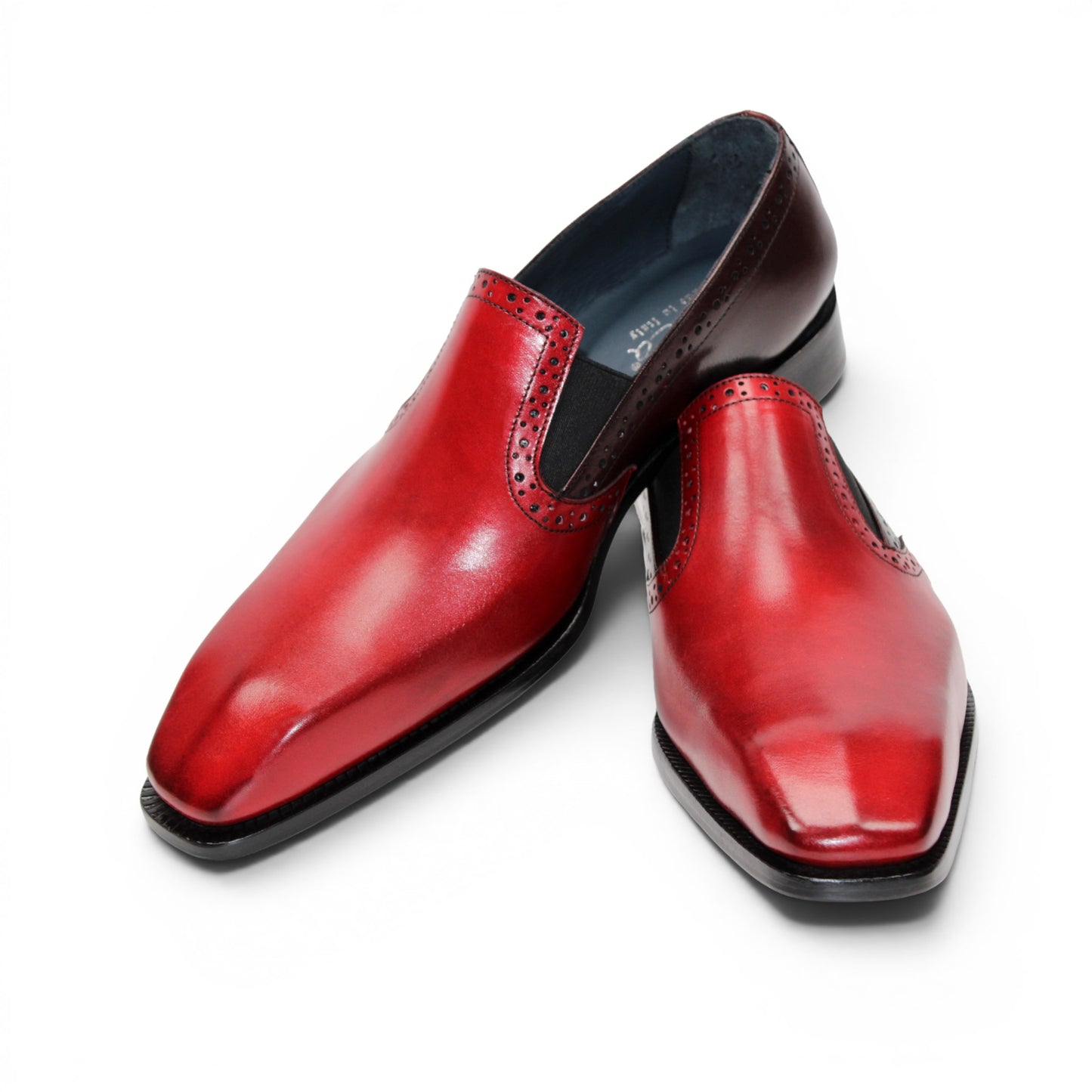 The Duca Di Matiste Duca Paliano Red/Burgundy is a men’s slip-on dress shoe in fine calf leather, featuring a red and dark brown upper with decorative perforations and a black low heel—Italian-made timeless style.