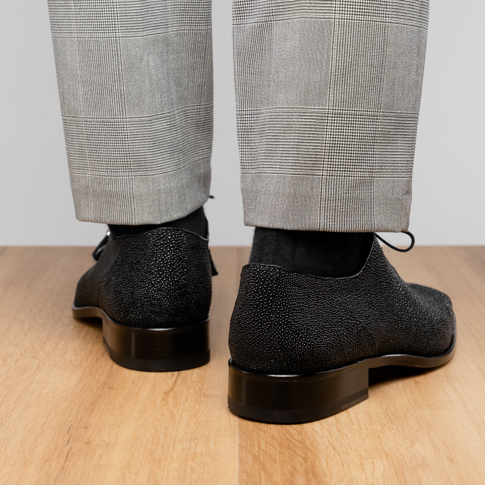 A pair of Rimini Black luxury dress shoes by Marco Di Milano, featuring a black textured finish and lace-up closure—one shoe displayed upright while the other shows the brown leather sole with embossed branding.