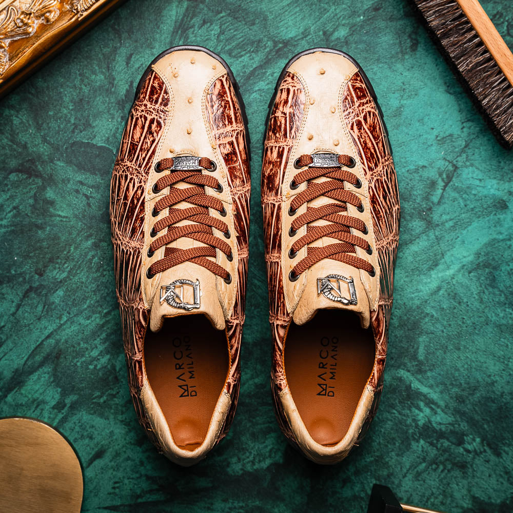 A pair of Saulo Orix men's shoes by Marco Di Milano, featuring brown crocodile-pattern leather and black rubber soles; one shoe stands upright while the other leans against it.