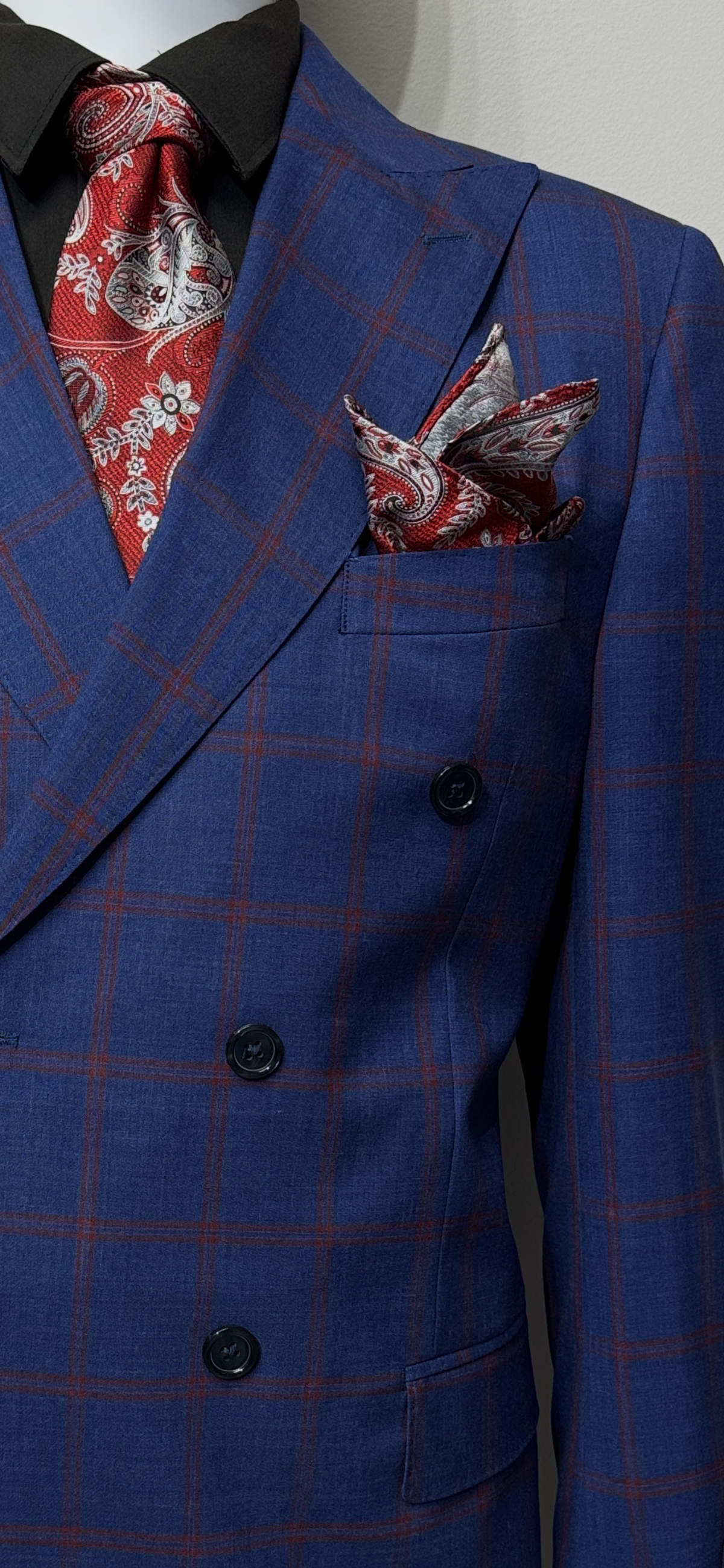 A Tiglio Luxe PISTOIA Modern Fit Double Breasted Suit (TL8074) in navy blue plaid, styled with a black shirt, red paisley tie, and matching pocket square.