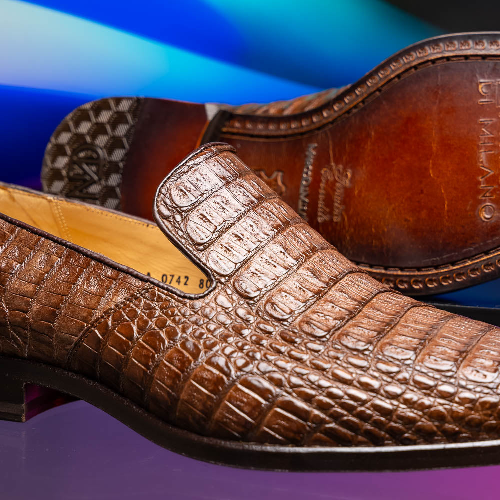 The Marco Di Milano Trento Brown shoes, crafted from genuine caiman crocodile leather, are shown with one upright and one on its side to reveal the sole, highlighting their hand-painted luxury finish.