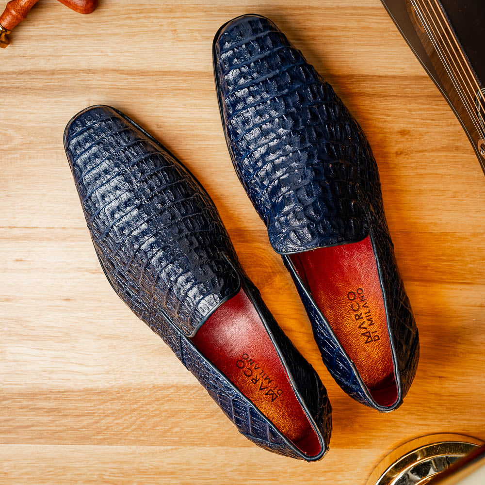 The Trento Navy by Marco Di Milano are dark blue genuine caiman leather loafers featuring hand-painted finishes, red lining, and "Marco Di Milano" branding on the sole.