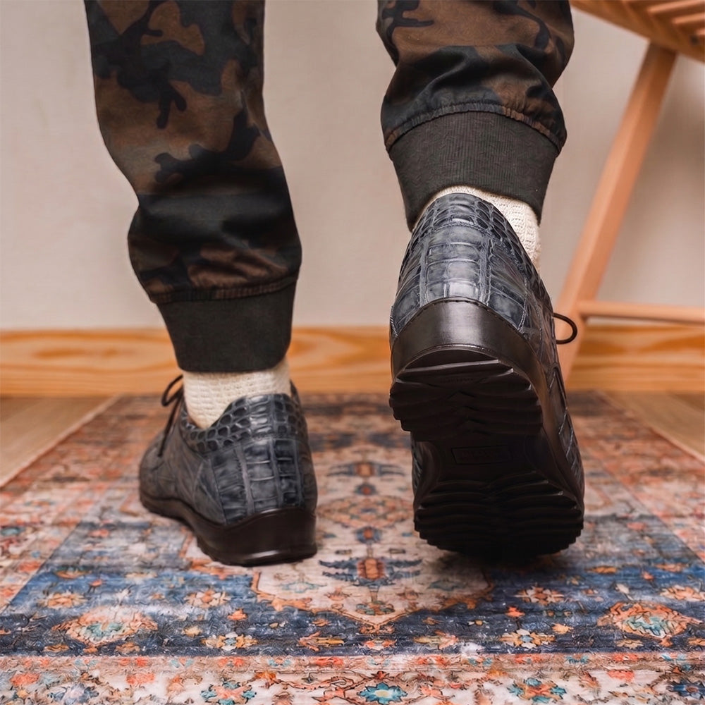 A pair of Marco Di Milano Vulcan Rustic Gray men's dress shoes, showcasing luxury footwear with crocodile-patterned leather, hand-painted finishes, and metal lace accents—one upright, one on its side to display the sole.