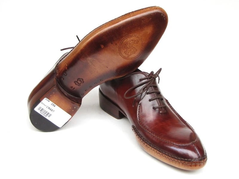 A pair of Paul Parkman Side Handsewn Split-toe Burgundy Oxfords (054-BUR), designed as men's oxfords with laces, featuring a raised heel and stitched details on the soles.