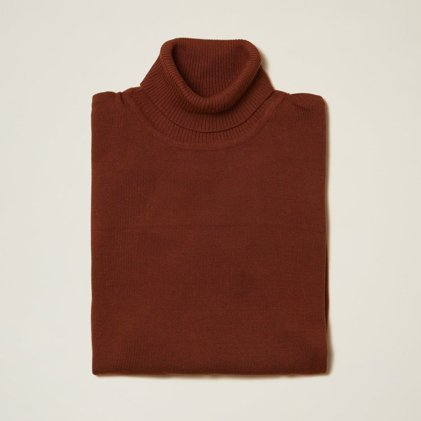 The Inserch Cotton Blend Turtleneck Sweater Aztec 4708, a folded brown turtleneck made from a cozy cotton blend by Inserch, is ideal for fall fashion. It is set against a light background.