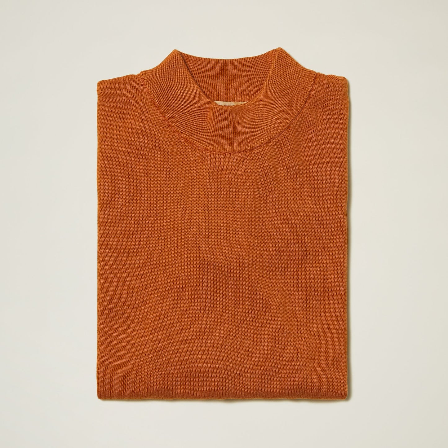 The Inserch Cotton Blend Mock Neck Sweater in rust (4308-00035), crafted from a soft cotton blend, is neatly folded against a plain background.